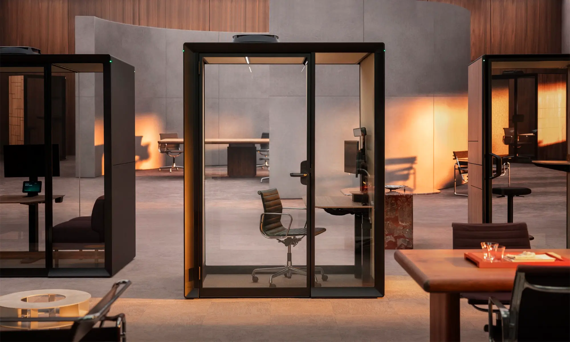 A modern open-plan office featuring glass-walled Framery Gradus pods and working desks.