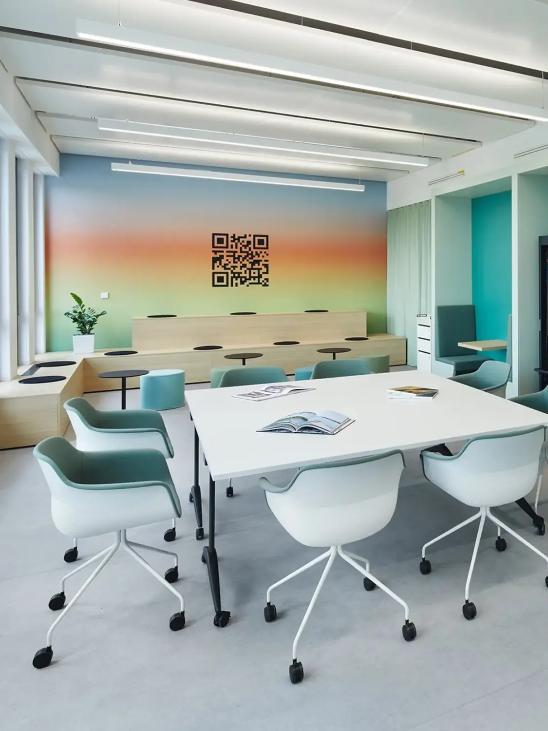 Bright modern conference room with a long white table, teal and white swivel chairs, a gradient rainbow wall with a QR code, and large windows.