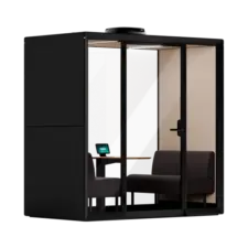 A Framery Gradus Huddle smart and soundproof huddle room with a desk, chair, laptop, and sofa inside.