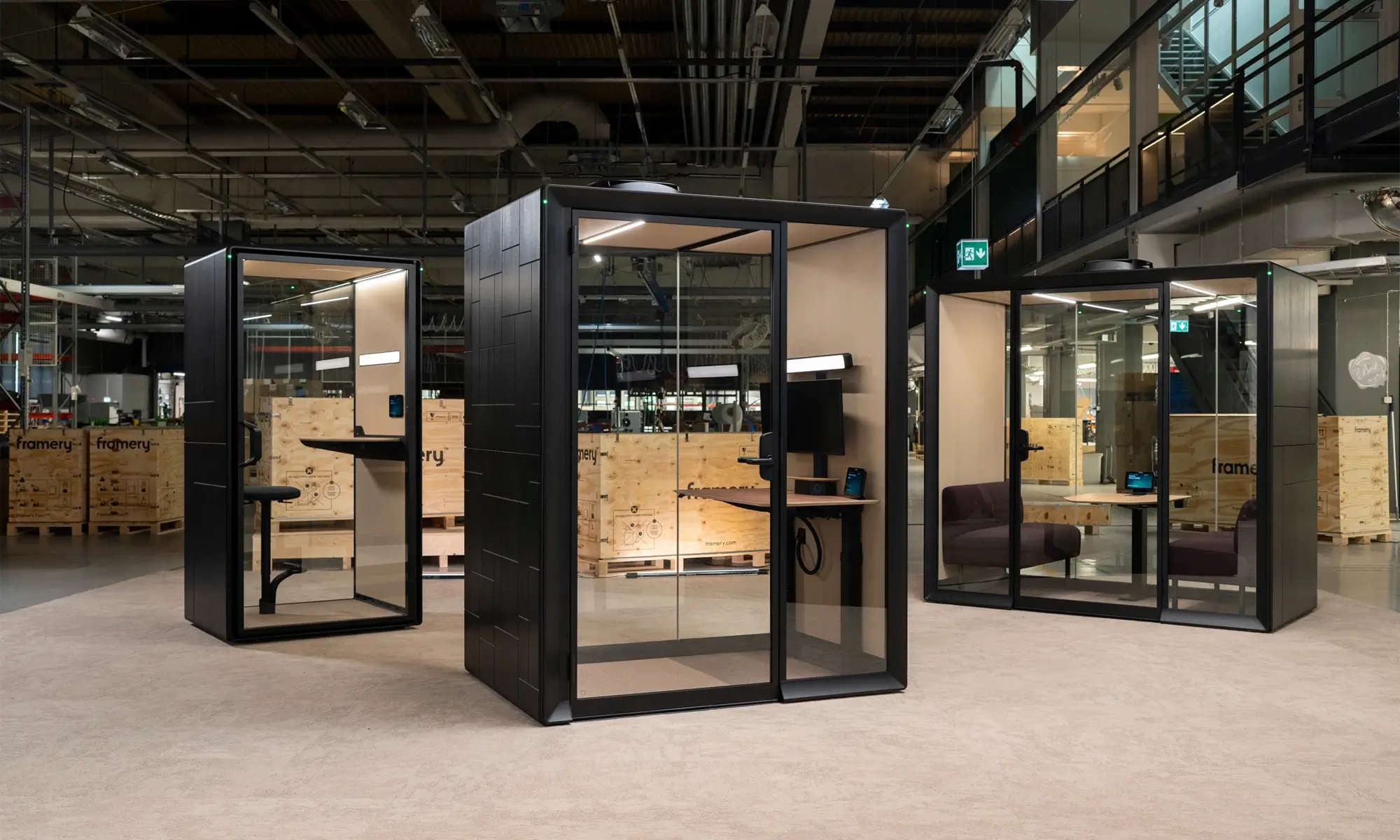 Empty industrial-style workspace featuring three Framery Gradus office pods with black frames in a spacious warehouse.