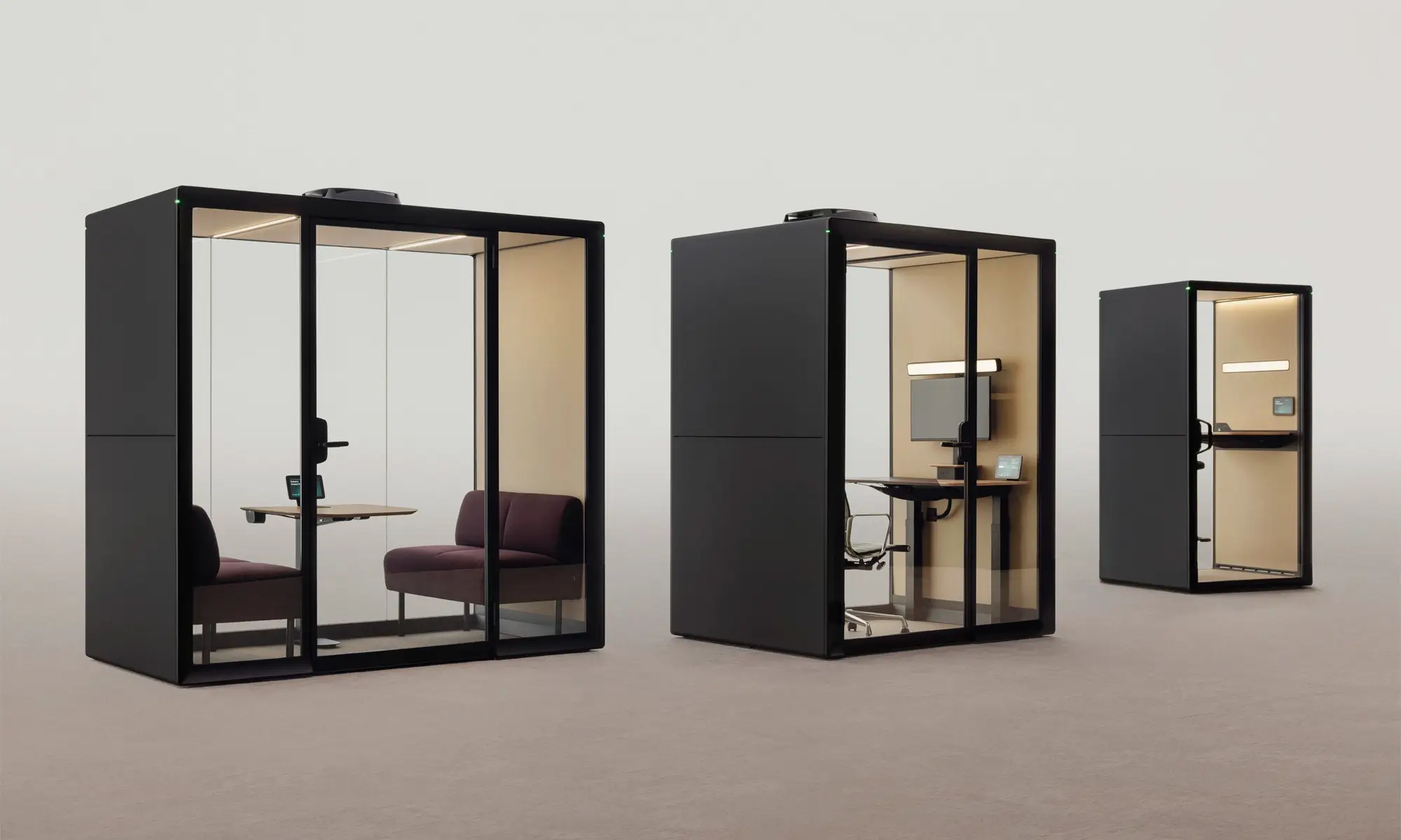 Three glass-fronted Framery Gradus modular office pods in a row with dark frames, varying in size and furnished with desks and chairs.