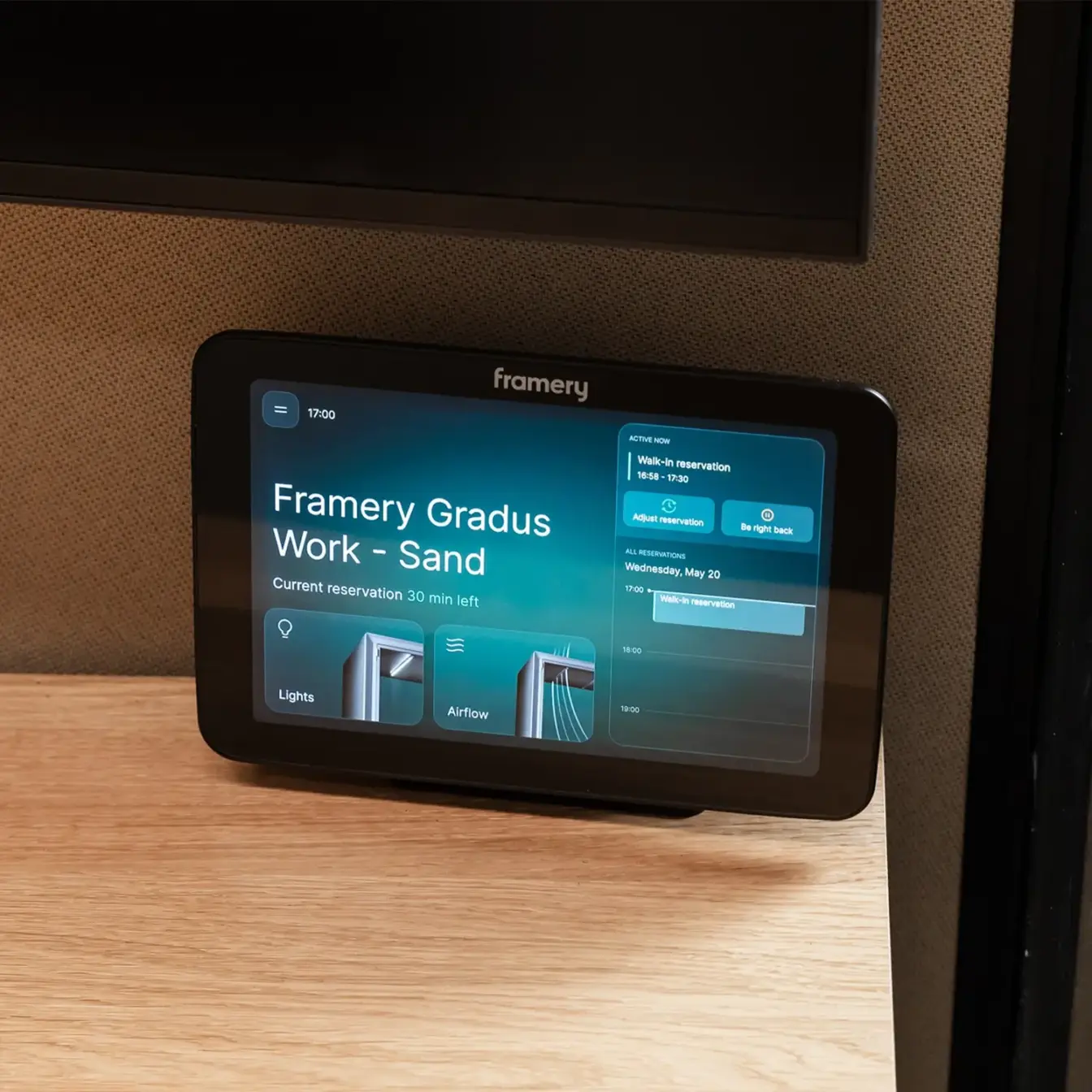 A Framery Gradus Work pods touchscreen display on a wooden desk showing the Gradus Work interface.