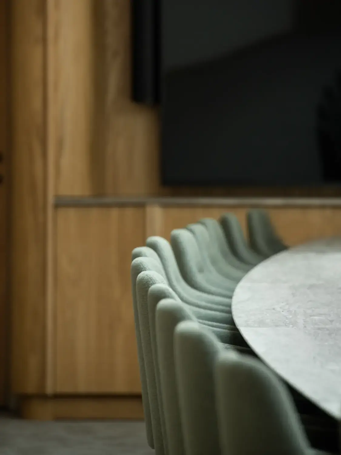 Several green upholstered chairs line the side of a round table in a wood-paneled room.