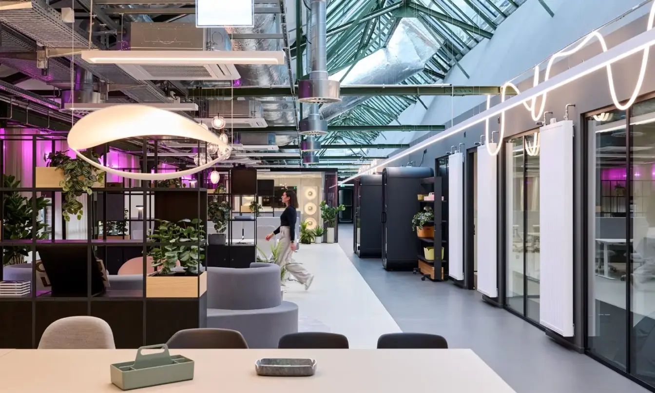 A modern tech office with vibrant lighting, colorful decor and a glass ceiling.