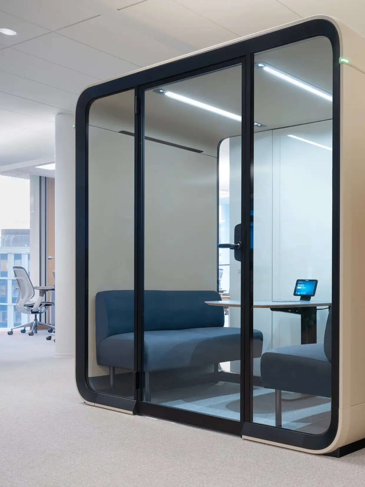 A sand color Framery Four meeting pod in an office setting.