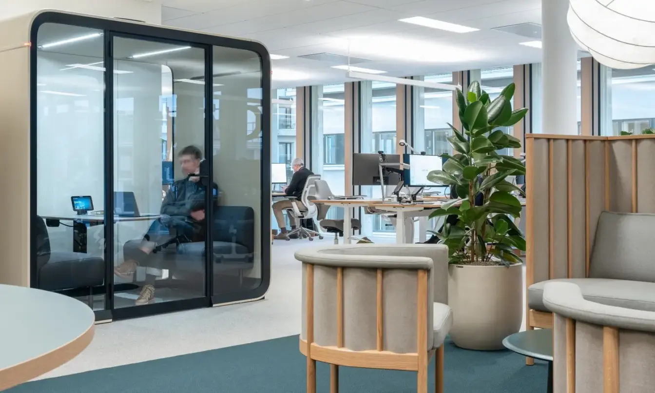 A Scandinavian style office interior with warm wooden furniture, light colors and a Framery Four soundproof office pod.