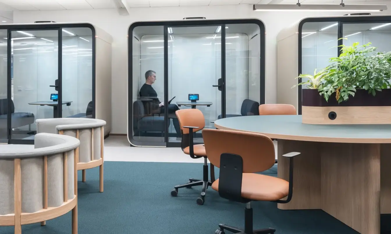 A Scandinavian style office interior with warm wooden furniture, light colors and Framery Four meeting pods.