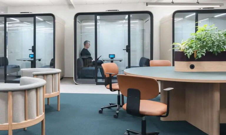 A Scandinavian style office interior with warm wooden furniture, light colors and Framery Four meeting pods.