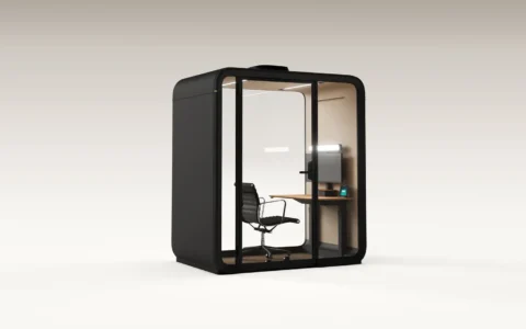 Compact glass-walled Framery One Work office workstation pod with a desk and chair inside.