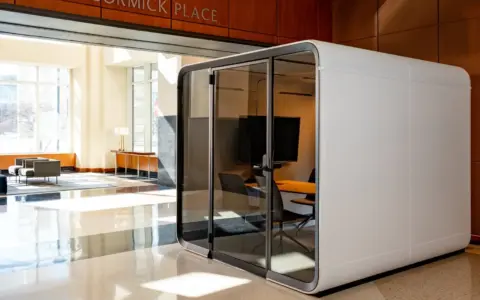 A white, glass-front Framery Six meeting pod sits in a bright, modern hotel lobby beneath a McCormick Place sign.