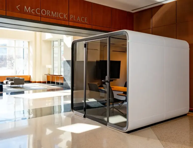 A white, glass-front Framery Six meeting pod sits in a bright, modern hotel lobby beneath a McCormick Place sign.