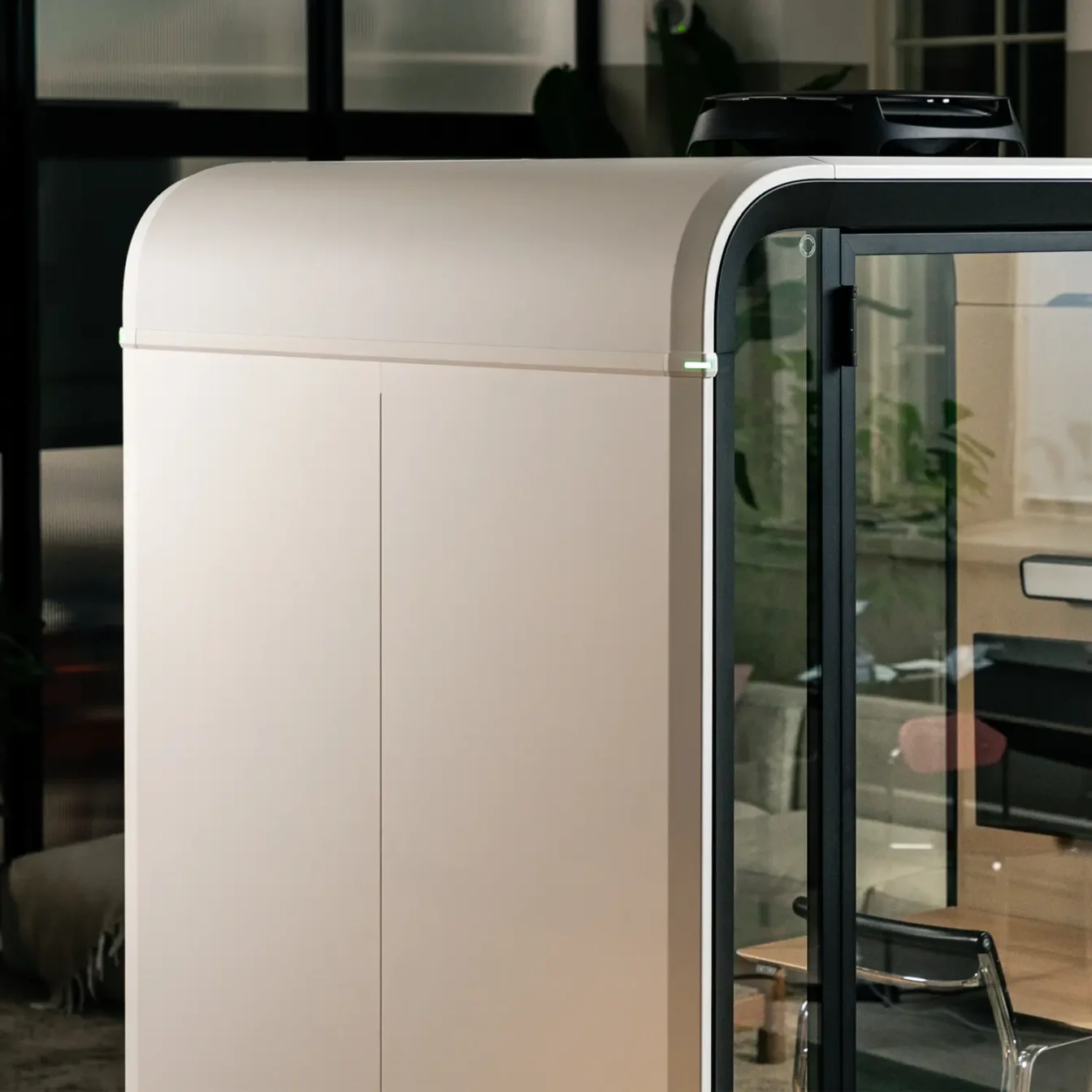 Beige curved Framery One Work workstation pod with a glass door showing interior shelves.