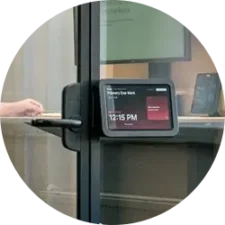 A Framery Room Display mounted on a glass door.